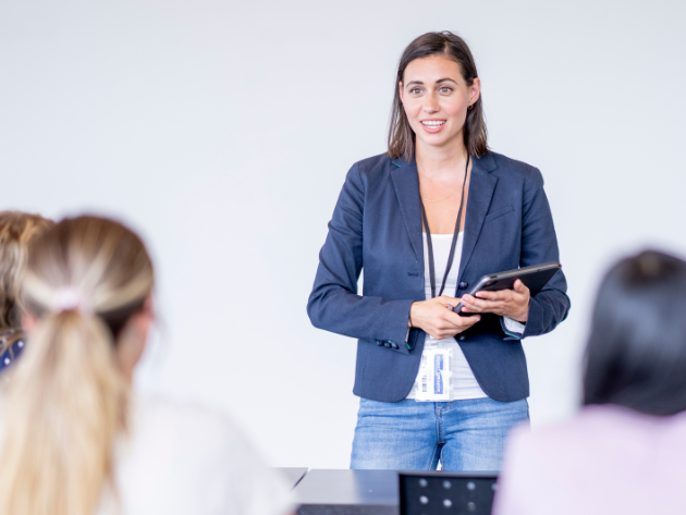 A woman standing in front of a classroom, representing law schools and reinvention in modern legal education.
