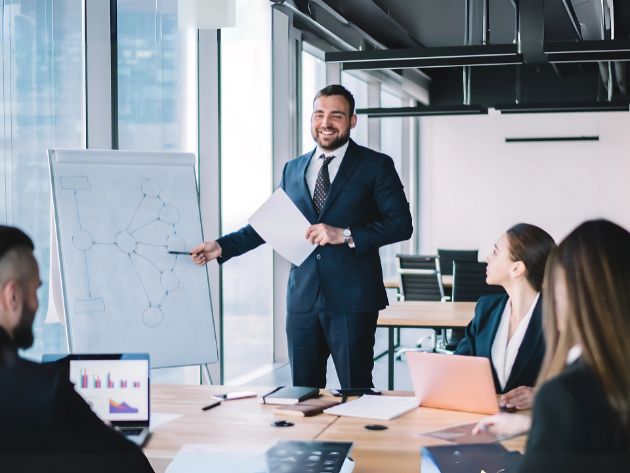 Leader presenting a project to a team in an office while receiving feedback, illustrating visible learning and iterative leadership in action